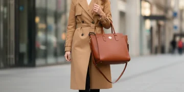 Woman in classic trench coat, tailored trousers, and leather tote bag