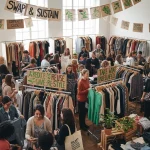 People happily participating in a vibrant clothing swap event, exchanging clothes and fostering community.